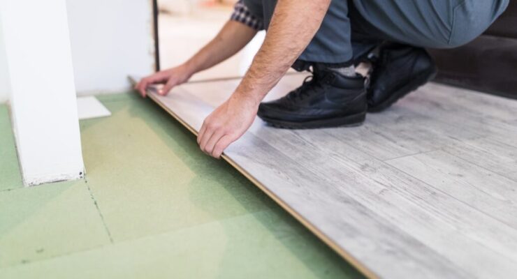 worker-processing-floor-with-laminated-flooring-boards-min